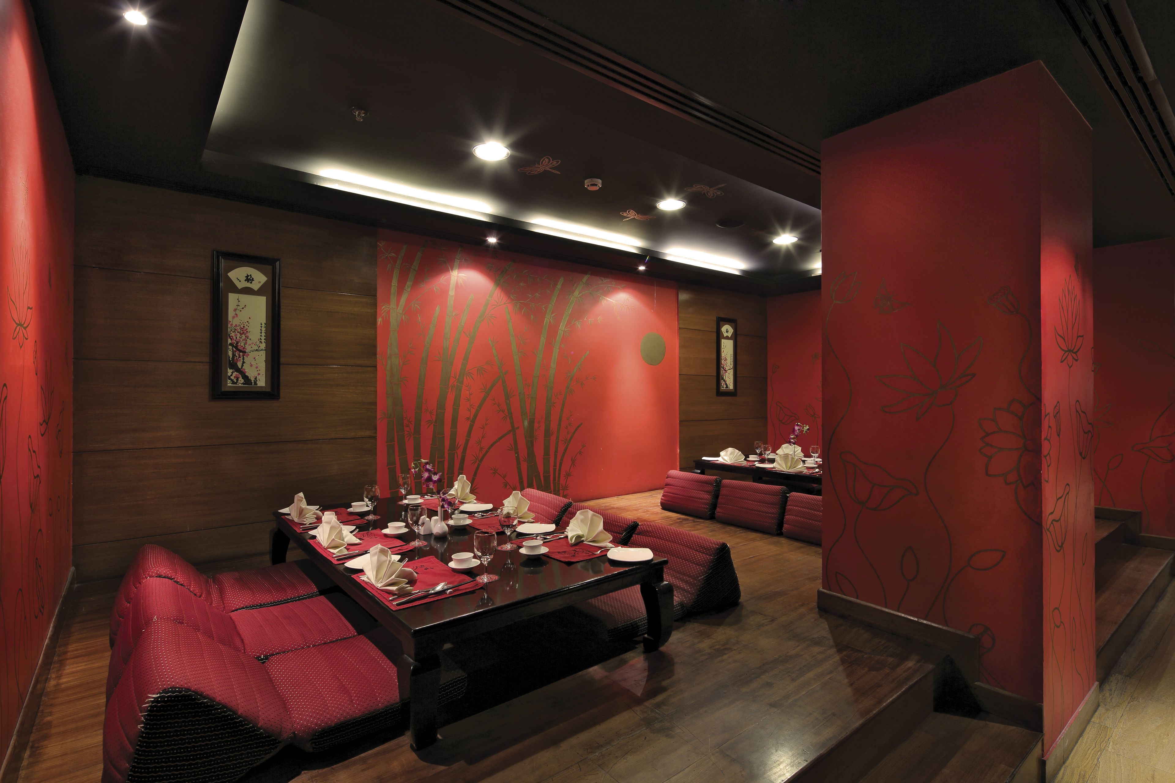 A dining area with a long table set for a meal, surrounded by red upholstered seating.