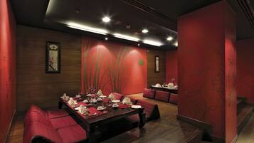 A dining area with a long table set for a meal, surrounded by red upholstered seating.