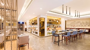 A modern hotel lobby with a central bar area, seating arrangements, and a decorative rope installation. - Radisson Jaipur City Center (Jaipur)