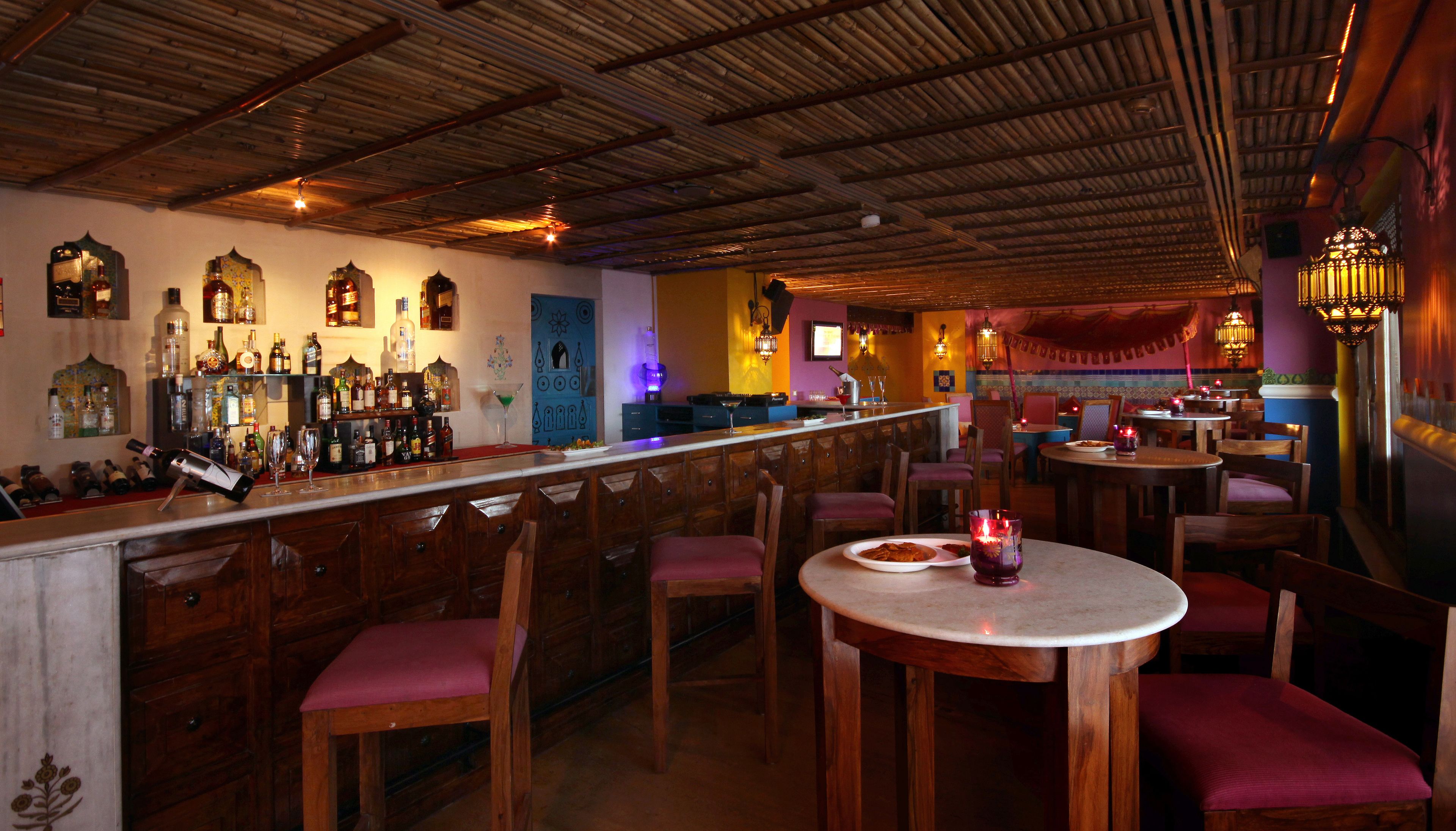 Uma área de bar com móveis de madeira, um balcão com garrafas e uma porta azul.