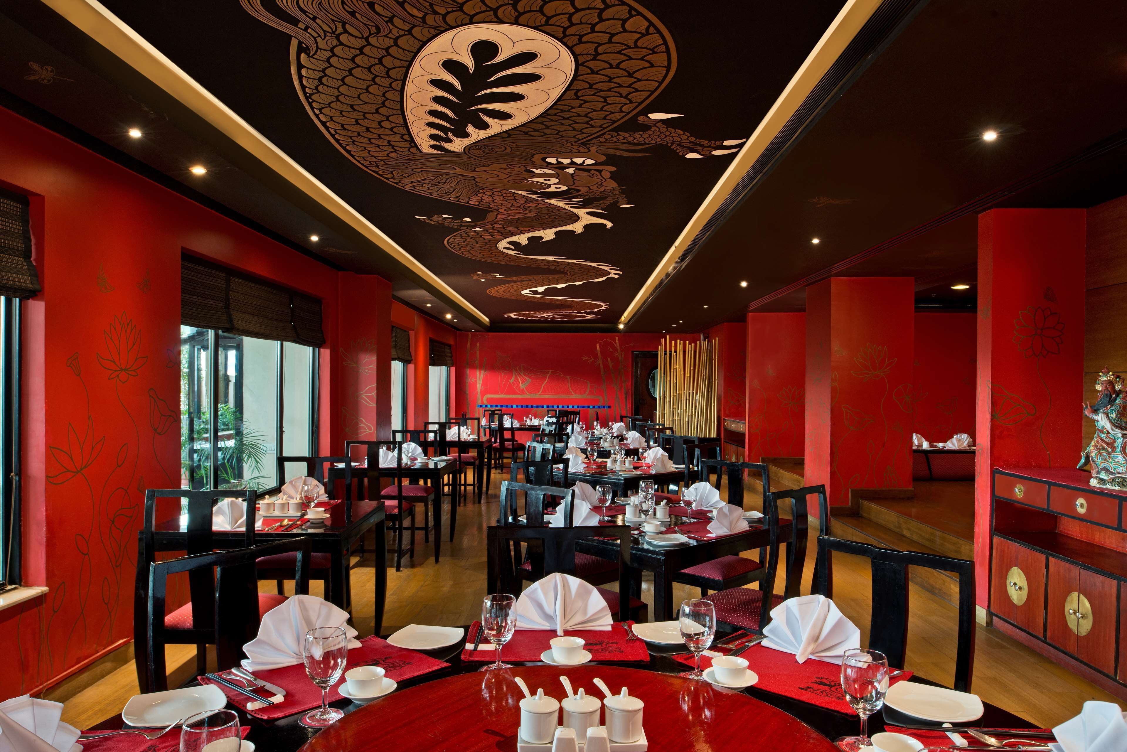 Un restaurante con paredes rojas, decoración en blanco y negro y mesas dispuestas para comer.