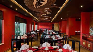 Un restaurante con paredes rojas, decoración en blanco y negro y mesas dispuestas para comer.