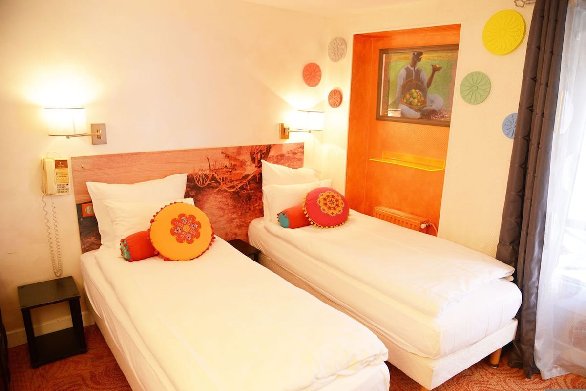 Una habitación de hotel con dos camas, un teléfono, un radiador y un cuadro en la pared.
