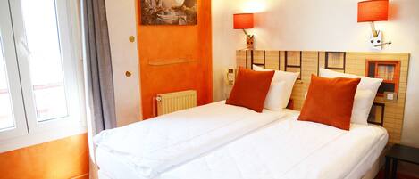 Een hotelkamer met een groot bed, twee bedlampen, een schilderij aan de muur en een raam met gordijnen.