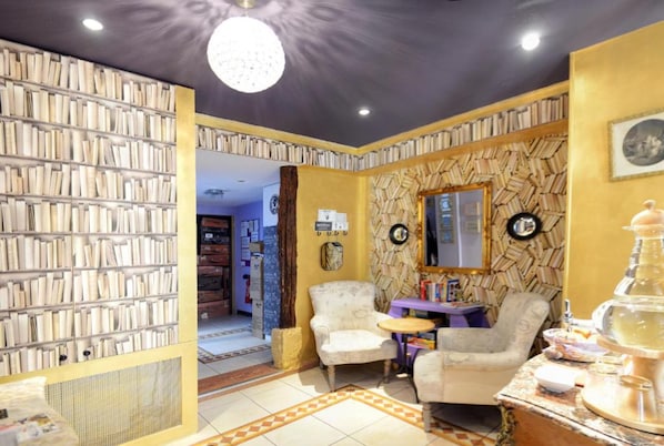 A cozy reading area with bookshelves, comfortable seating, and a decorative mirror.