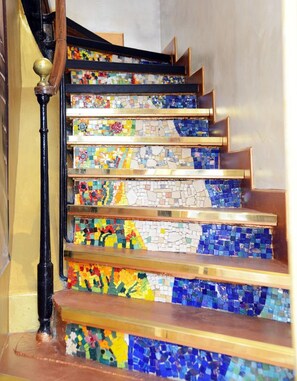 A staircase with colorful mosaic steps and a wooden handrail.