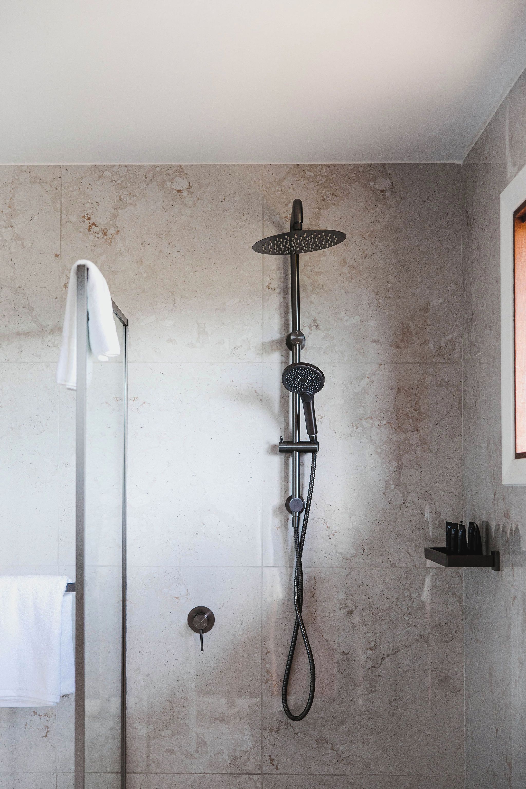 A modern shower with a rain showerhead, a handheld showerhead, and a handheld massager.