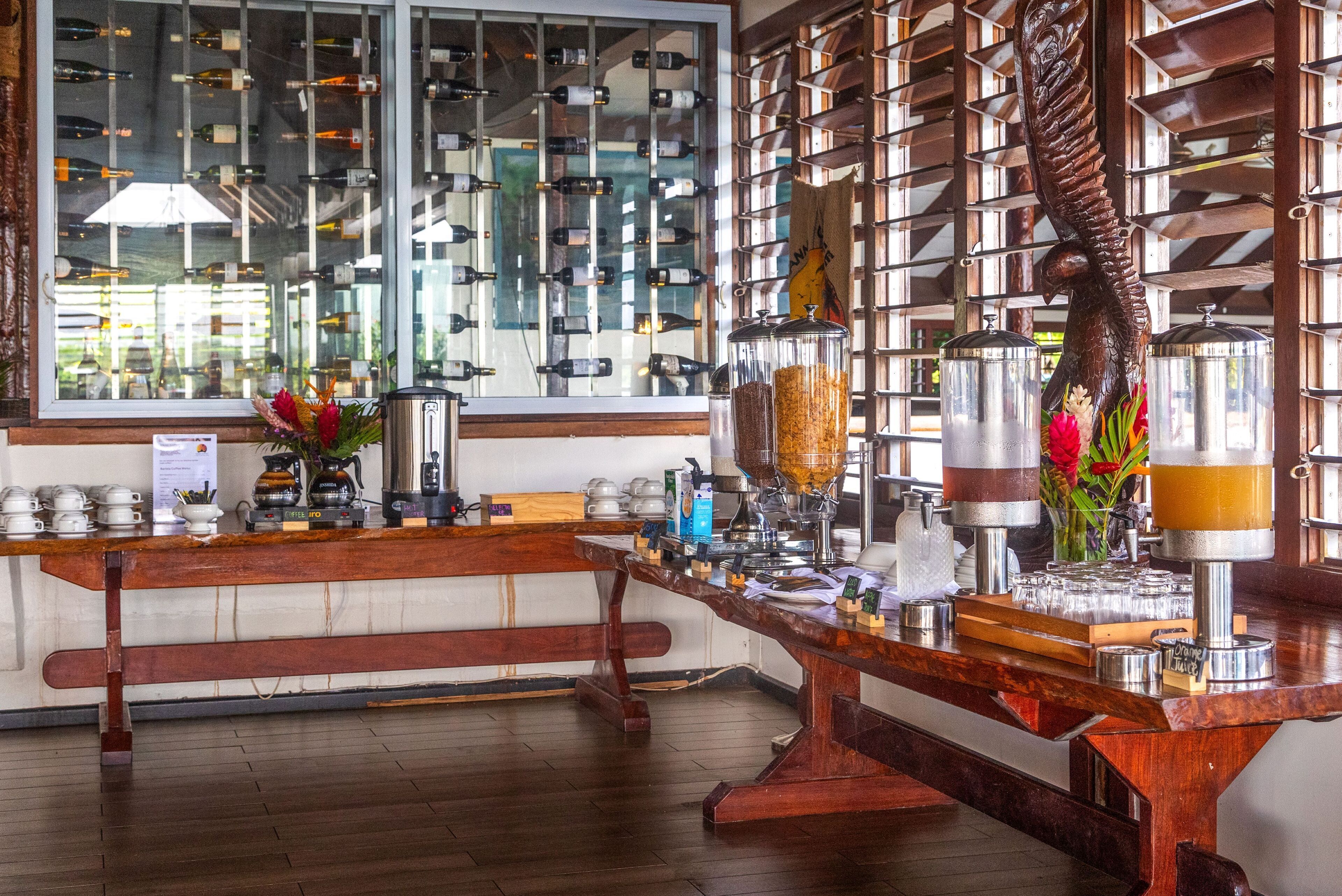 Una zona de bar con un banco de madera, una estantería para vinos y una máquina de café.