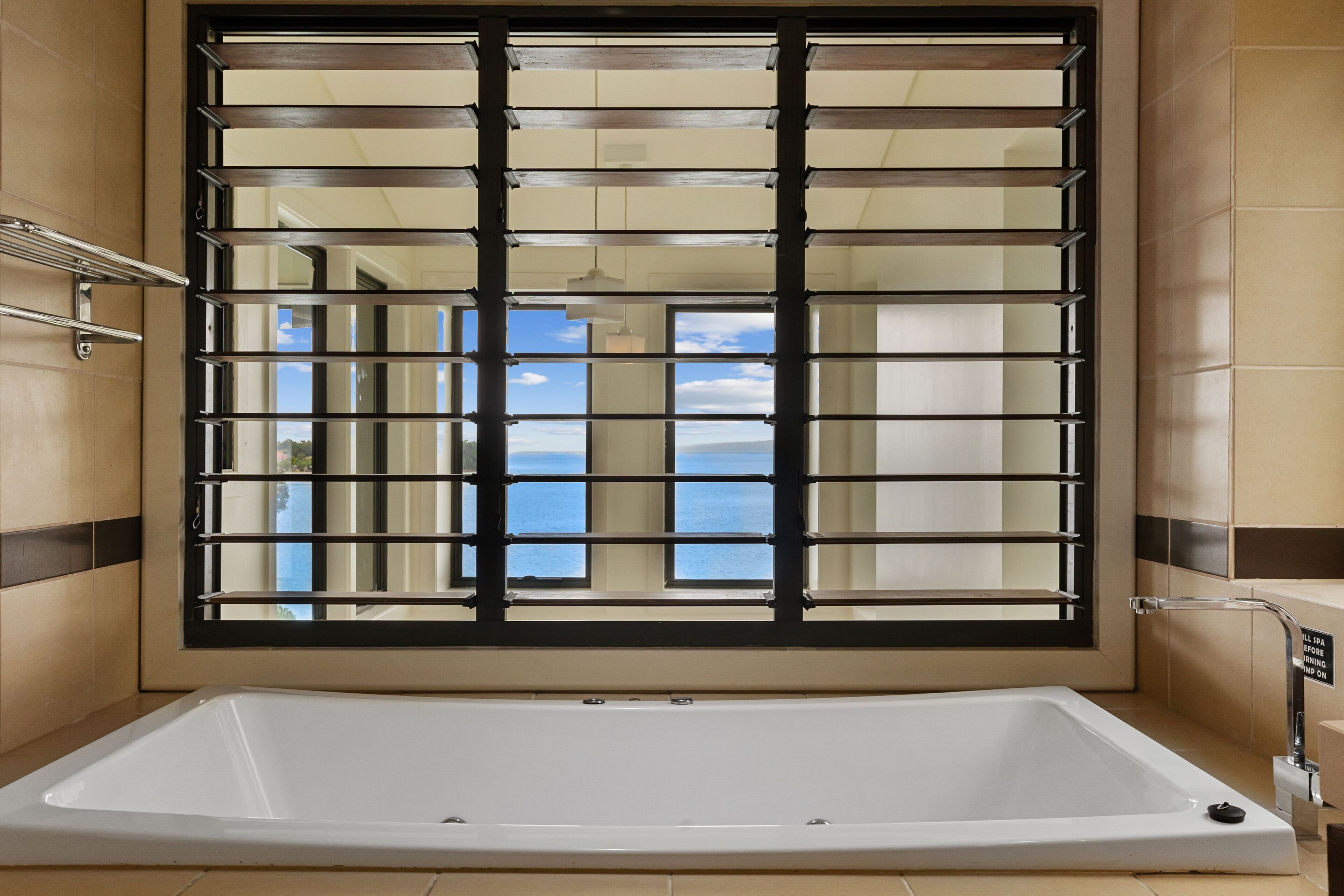 Une salle de spa dotée d’une grande baignoire, d’une fenêtre avec des barreaux et d’une vue sur le ciel.