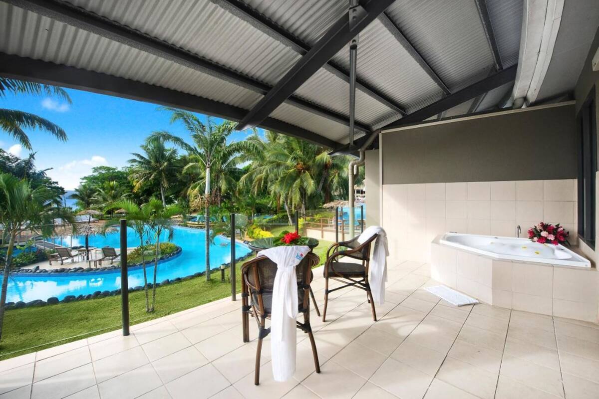 Ein überdachter Außenbereich mit Pool, Stühlen und einer Badewanne.