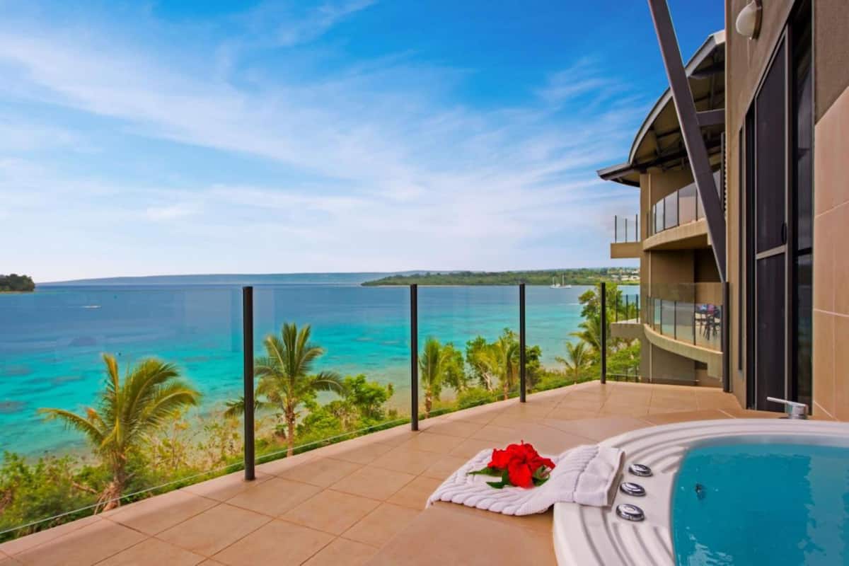 Ein Balkon mit Whirlpool, einer Rose und Blick auf das Meer.