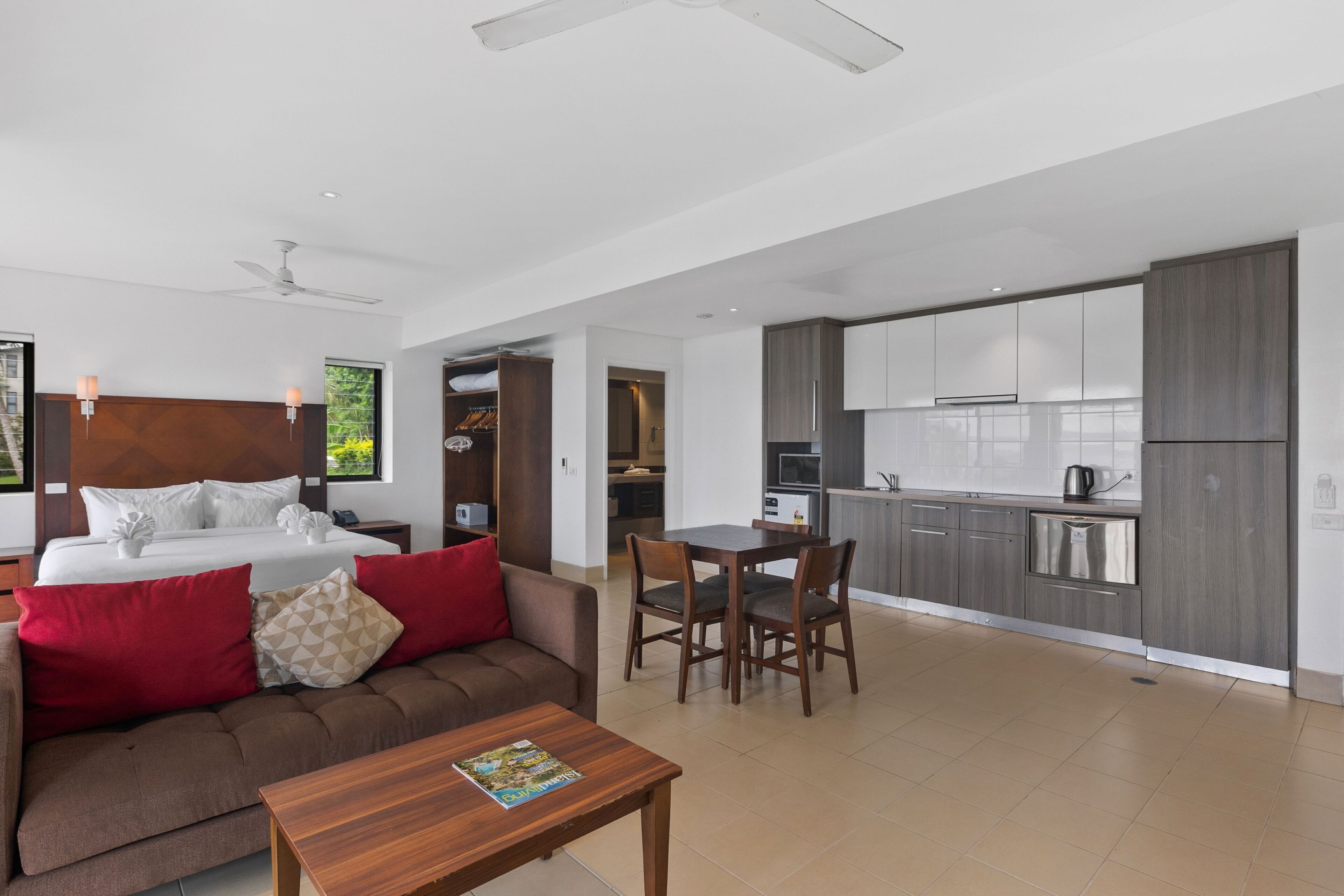 Una habitación de hotel moderna con cama, sofá, mesa de comedor y zona de cocina.