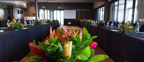 A conference room with long tables, floral centerpieces, and large windows.