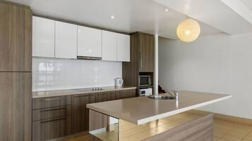 Una cocina moderna con armarios de madera, una isla grande y un colgante de luz.