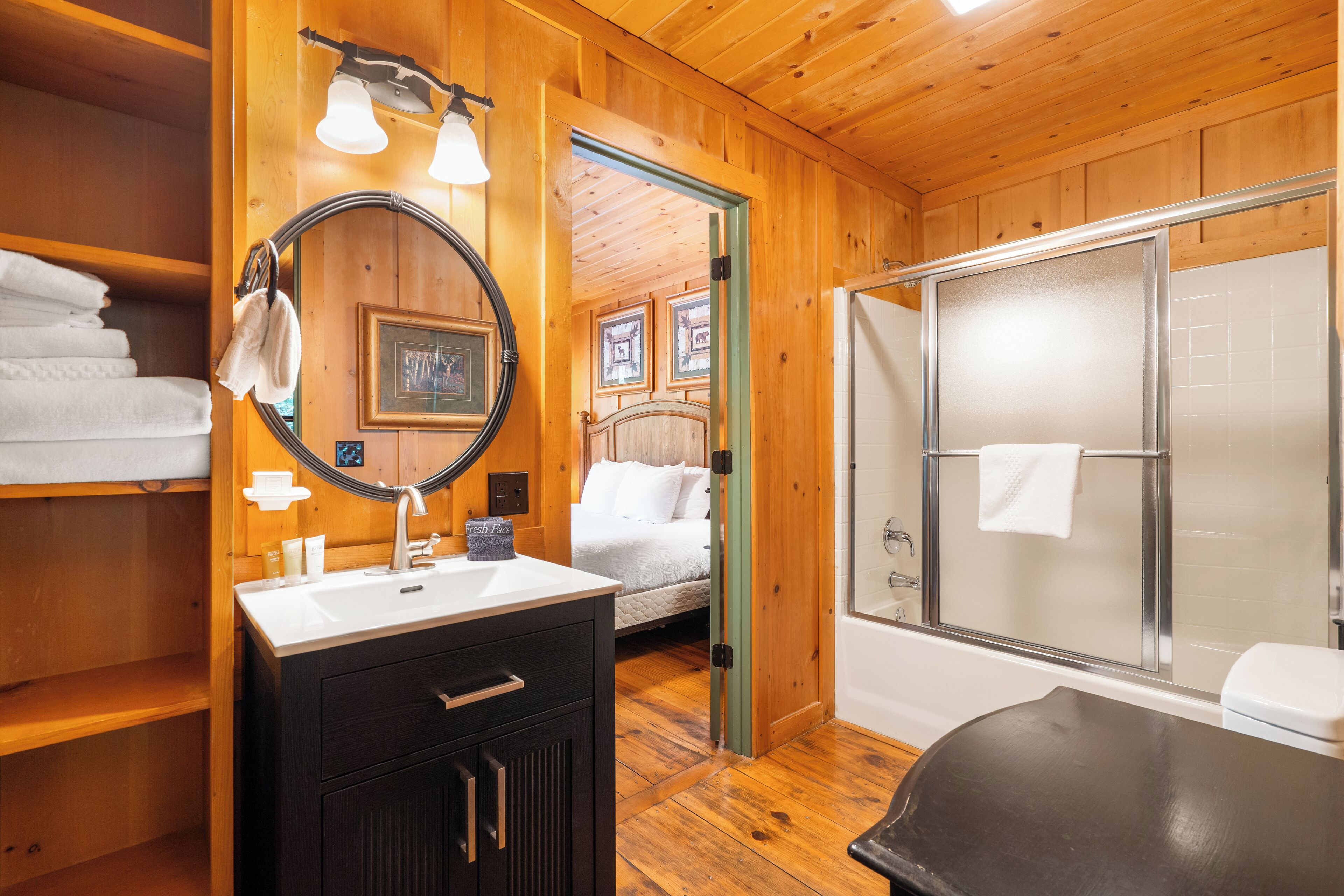 A wooden cabin bathroom with a sink, mirror, and shower.