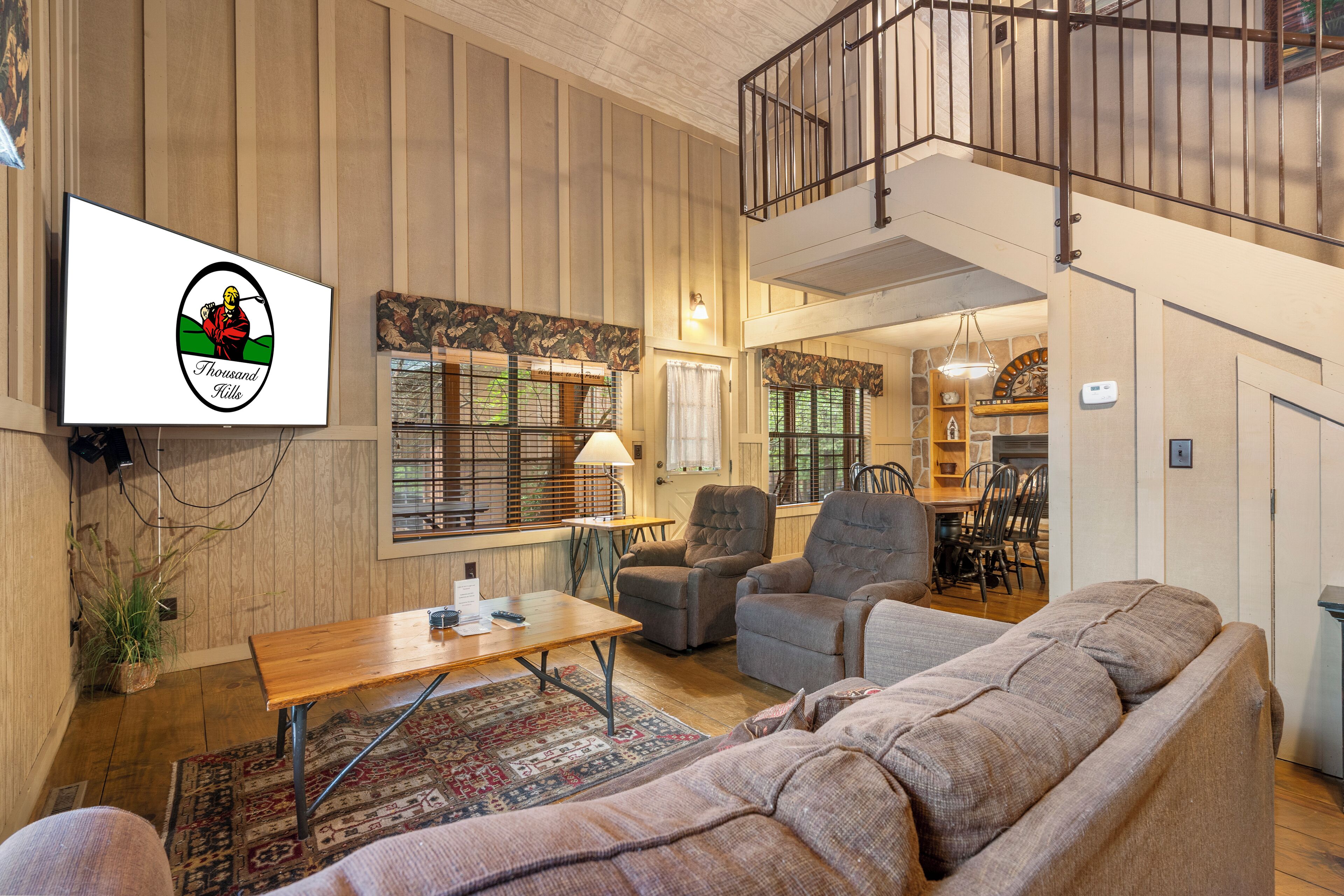 A spacious living area with a wooden floor, a sofa, a coffee table, and a television mounted on the wall.