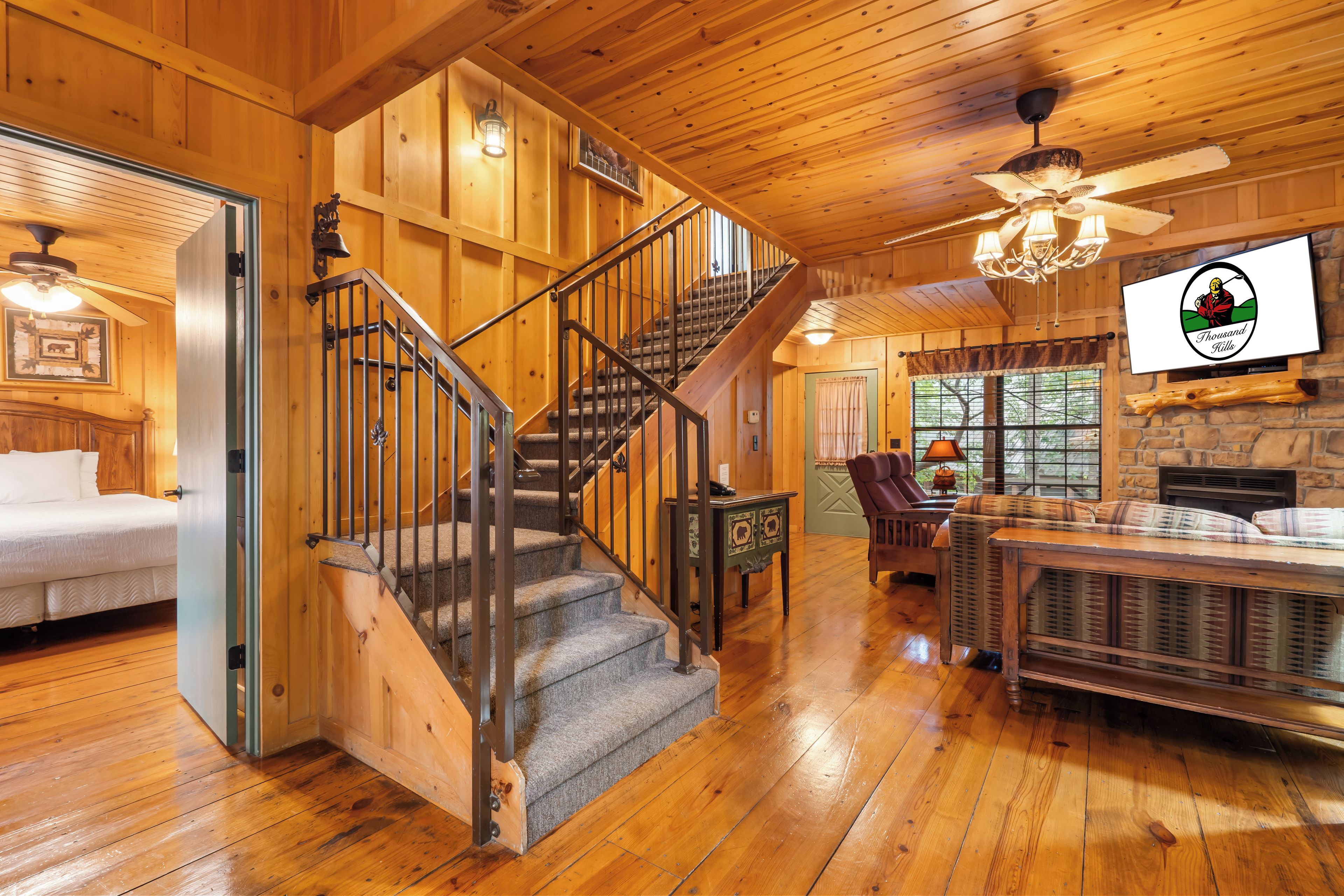 A wooden interior with a staircase, a fireplace, and a bed.