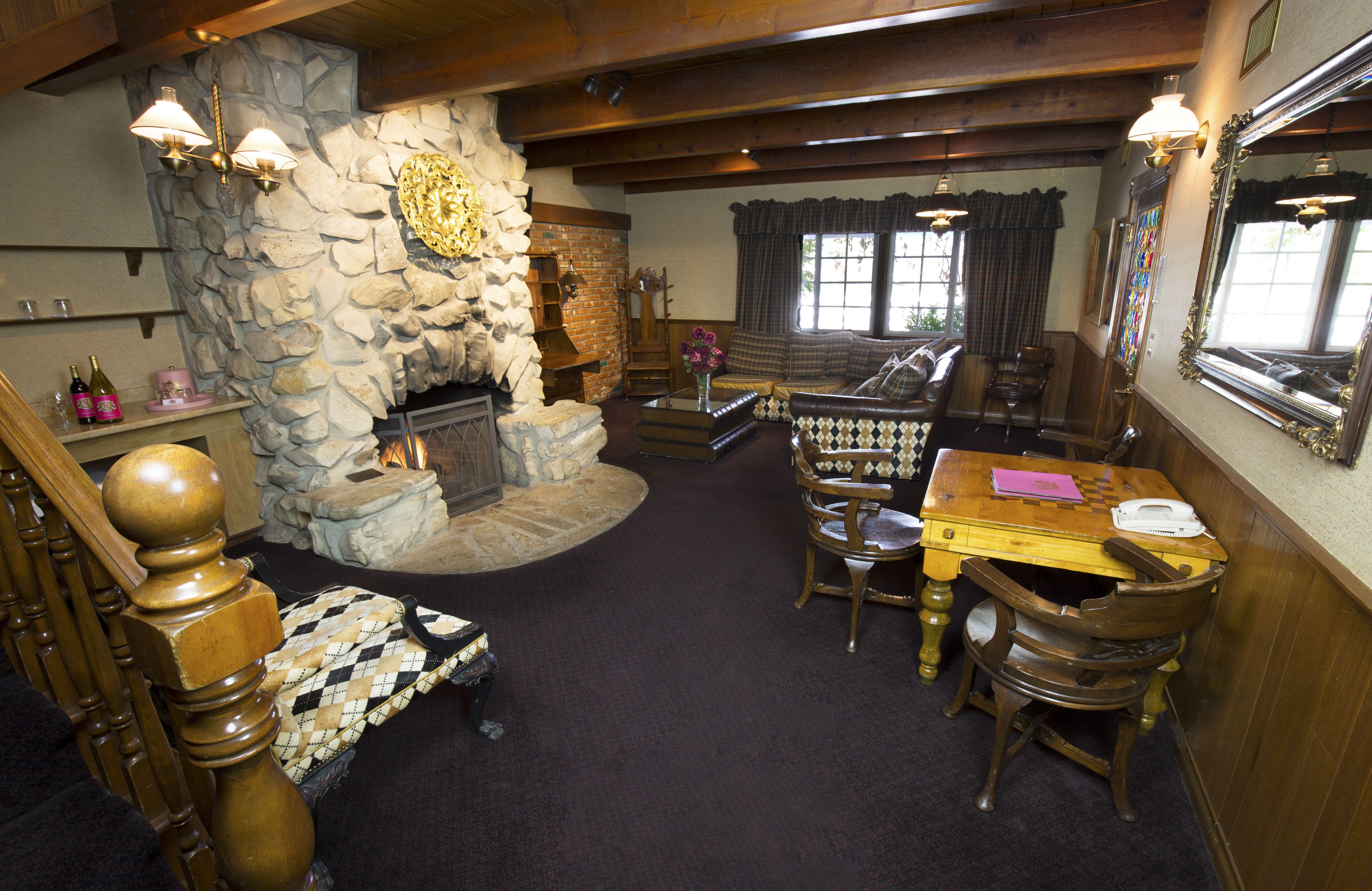 A cozy room with a stone fireplace, wooden furniture, and a large mirror.