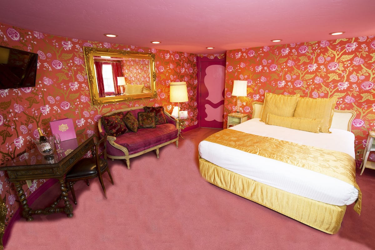 Ein Schlafzimmer mit einem großen Bett, einem Schminktisch mit Spiegel und einer Kommode.