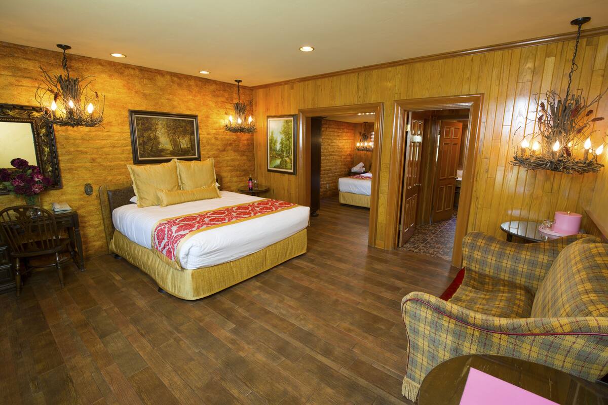 Ein Hotelzimmer mit einem großen Bett, einem Sessel, einem kleinen Tisch und einem Spiegel.