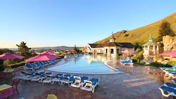 Relax by the serene pool surrounded by lounge chairs and shaded structures.