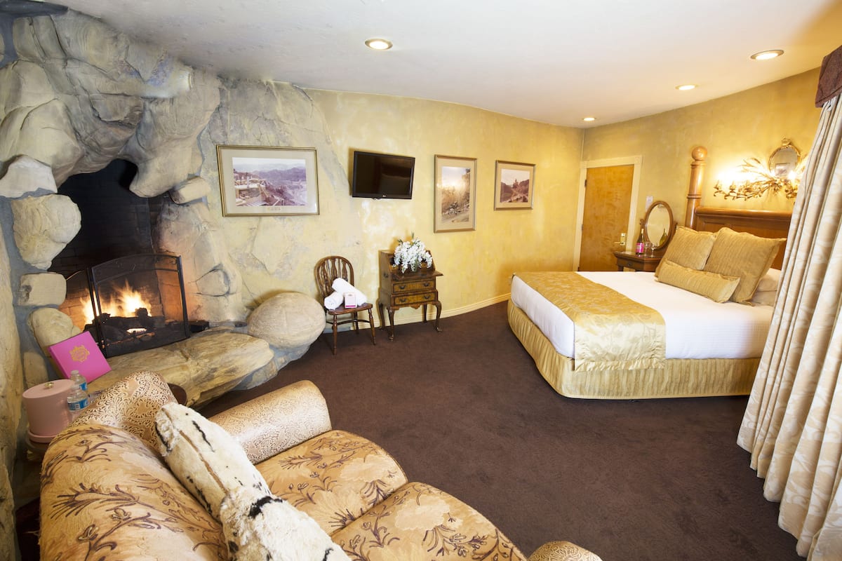Ein Schlafzimmer mit Steinstruktur, Kamin, Bett, Sofa und Fernseher.