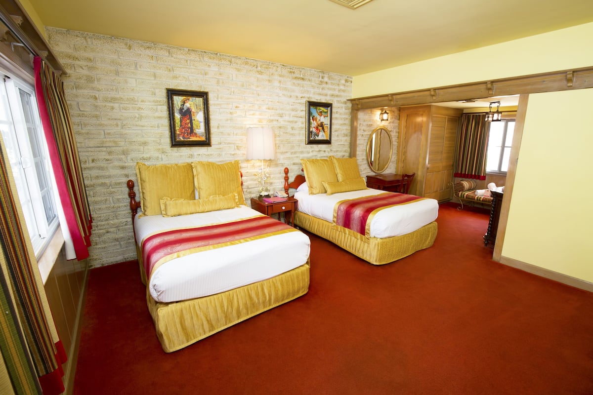 Ein Hotelzimmer mit zwei Betten, einer Ziegelwand und einem roten Teppich.