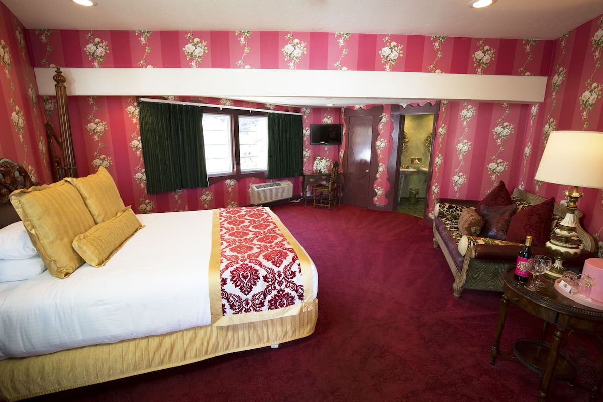 Ein Hotelzimmer mit einem großen Bett, einer Couch, einem Fernseher und einem kleinen Tisch mit einer Lampe.
