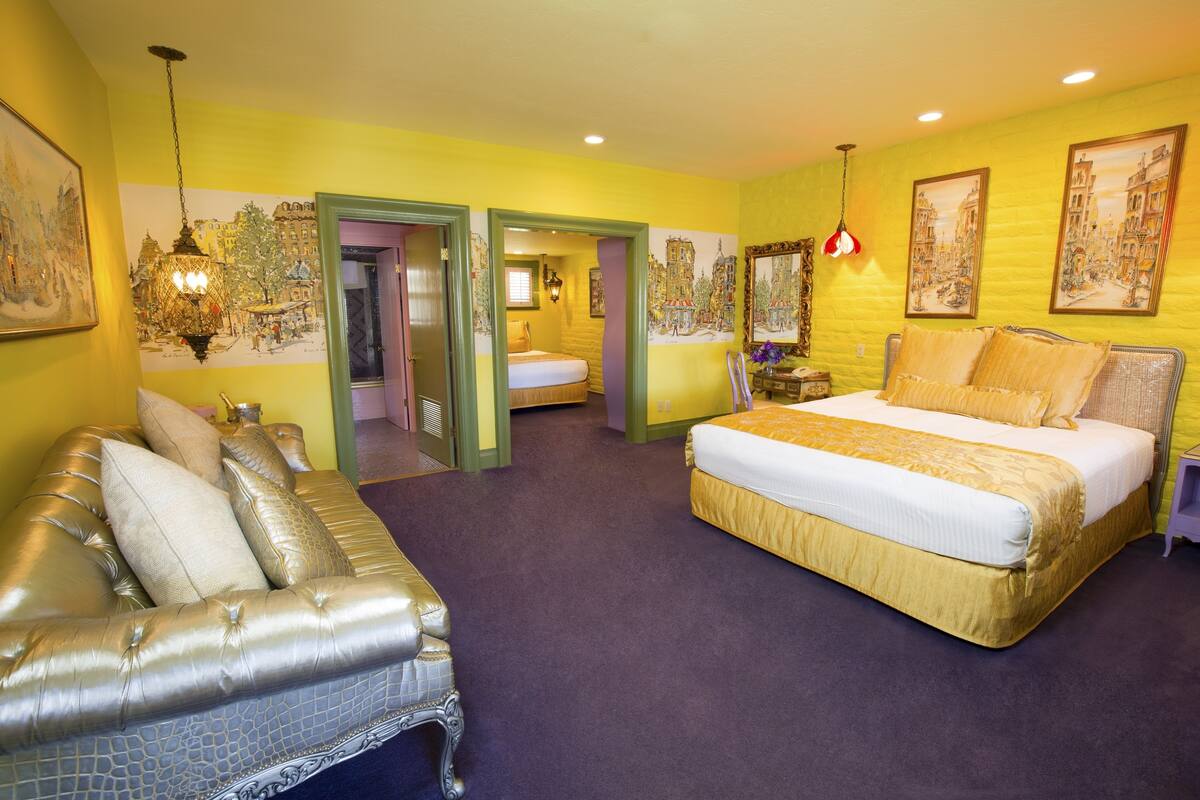 Ein Hotelzimmer mit einem großen Bett, einer Couch und einem durchgegangenen Tür erkennbaren Badezimmer.