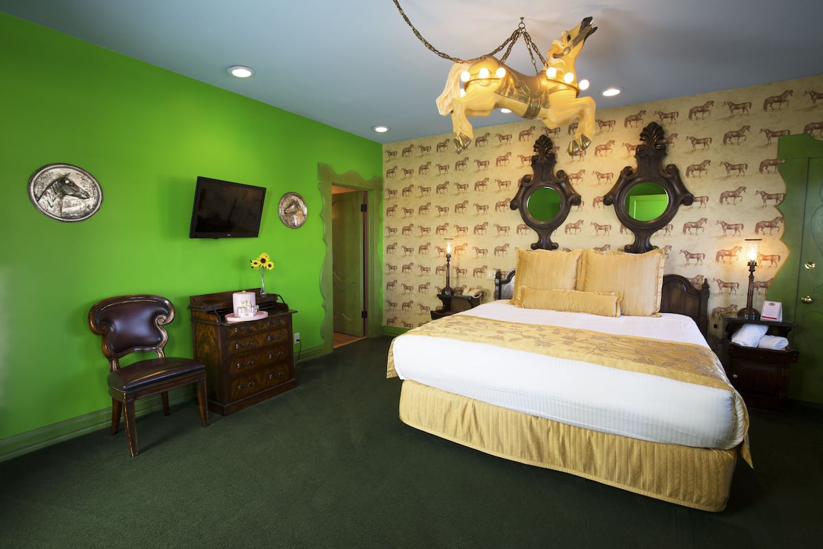 Ein Schlafzimmer mit einem großen Bett, einem Holzstuhl, einer Kommode und einem an der Wand befestigten Fernseher.