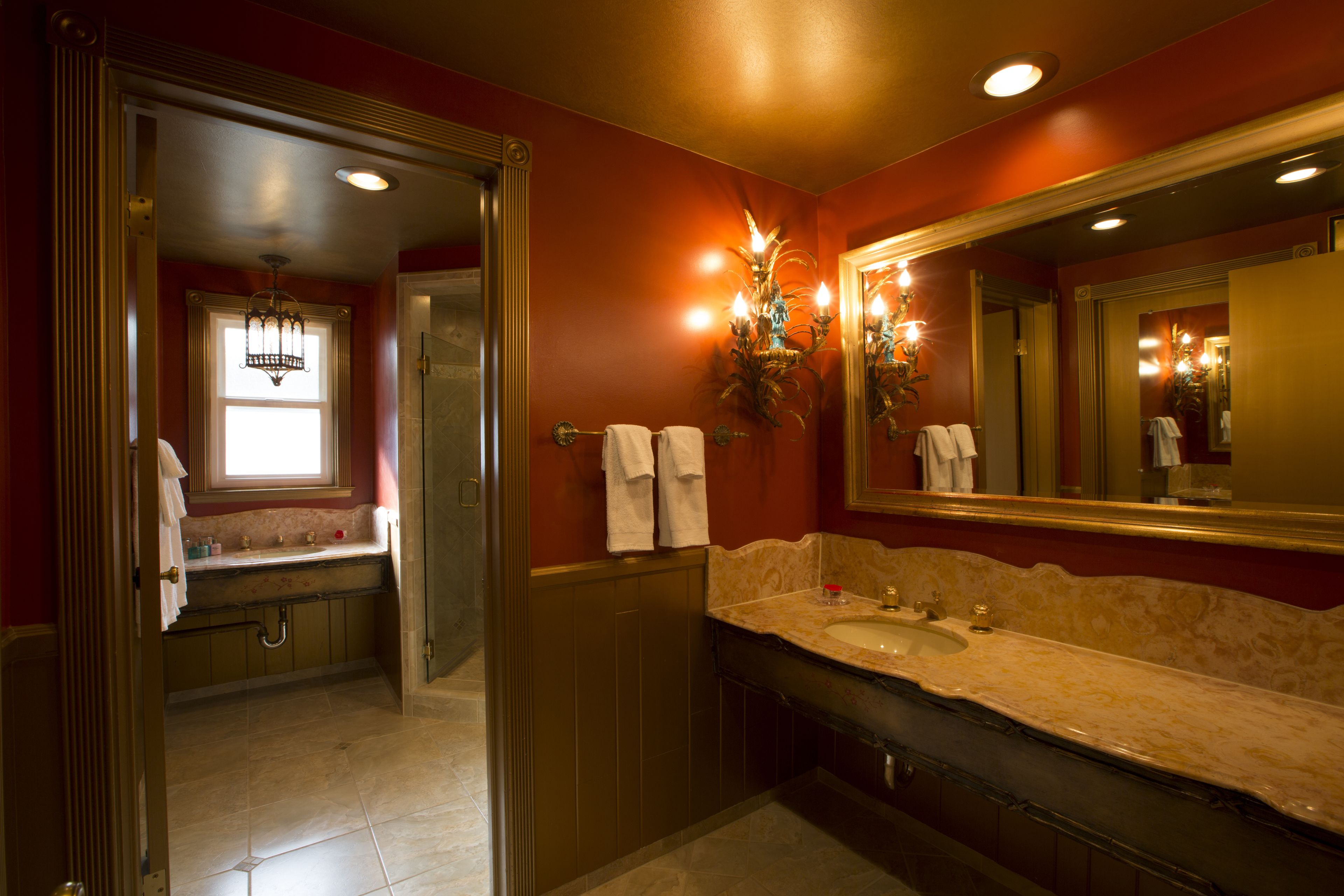 A bathroom with a large mirror, a sink, and a shower.