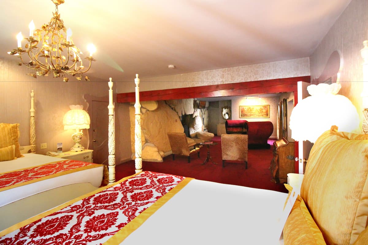 Ein Hotelzimmer mit einem großen Bett, einer Kristallleuchtre, einem roten Teppich und einer Sitzecke mit Stühlen und einem Tisch.