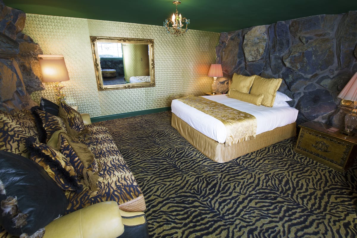 Ein Schlafzimmer mit einem Bett, einem Spiegel, einer Chandelieber und einer Steinwand.