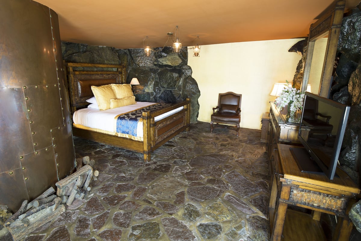 Ein Schlafzimmer mit Steinböden, einem Bett, einer hölzernen Kommode und einer Steinwand.