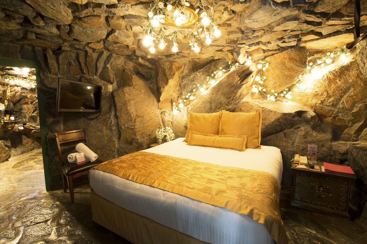 Ein Schlafzimmer mit Steinwänden, einem Bett, einem Fernseher und einem Nachttisch.