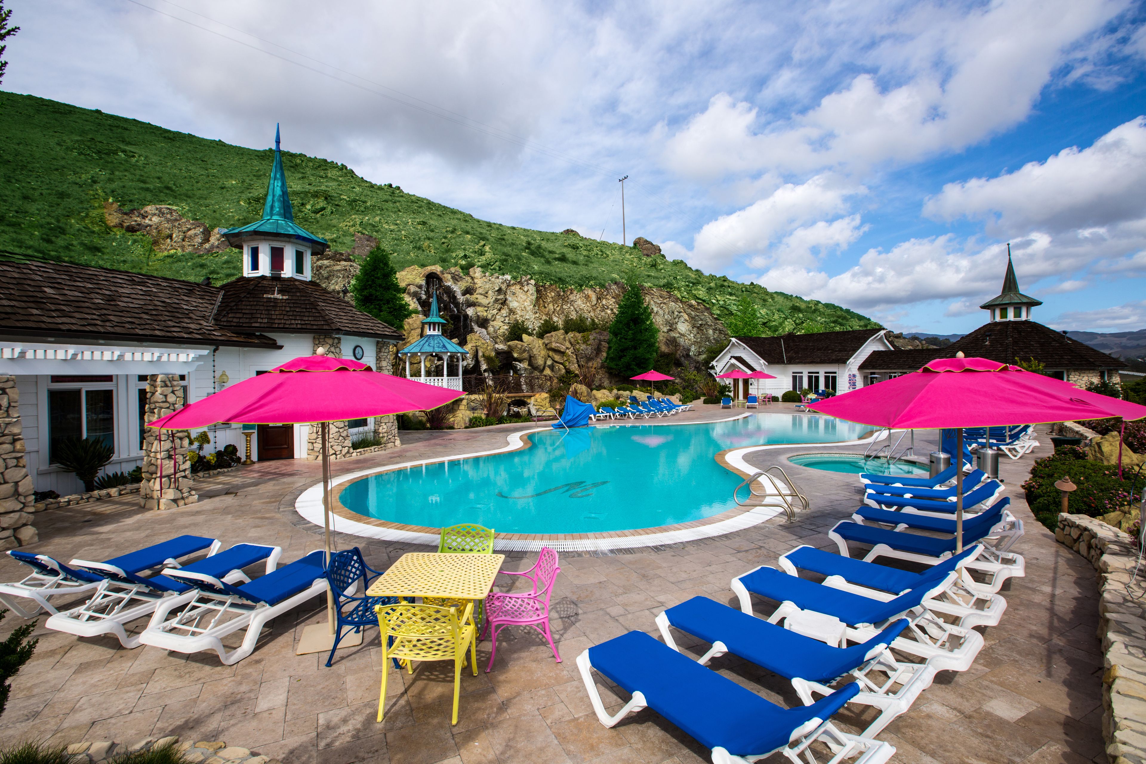 A pool area with lounge chairs and umbrellas, surrounded by buildings with distinct architecture.