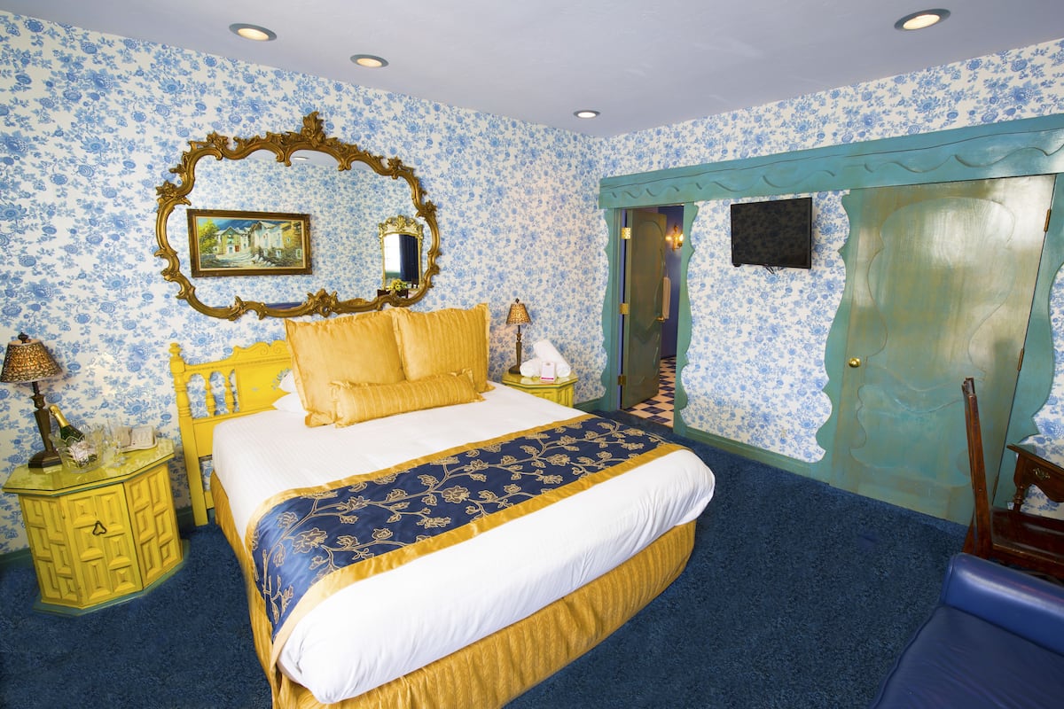Ein Schlafzimmer mit Bett, Nachttisch, Spiegel und einer Tür.