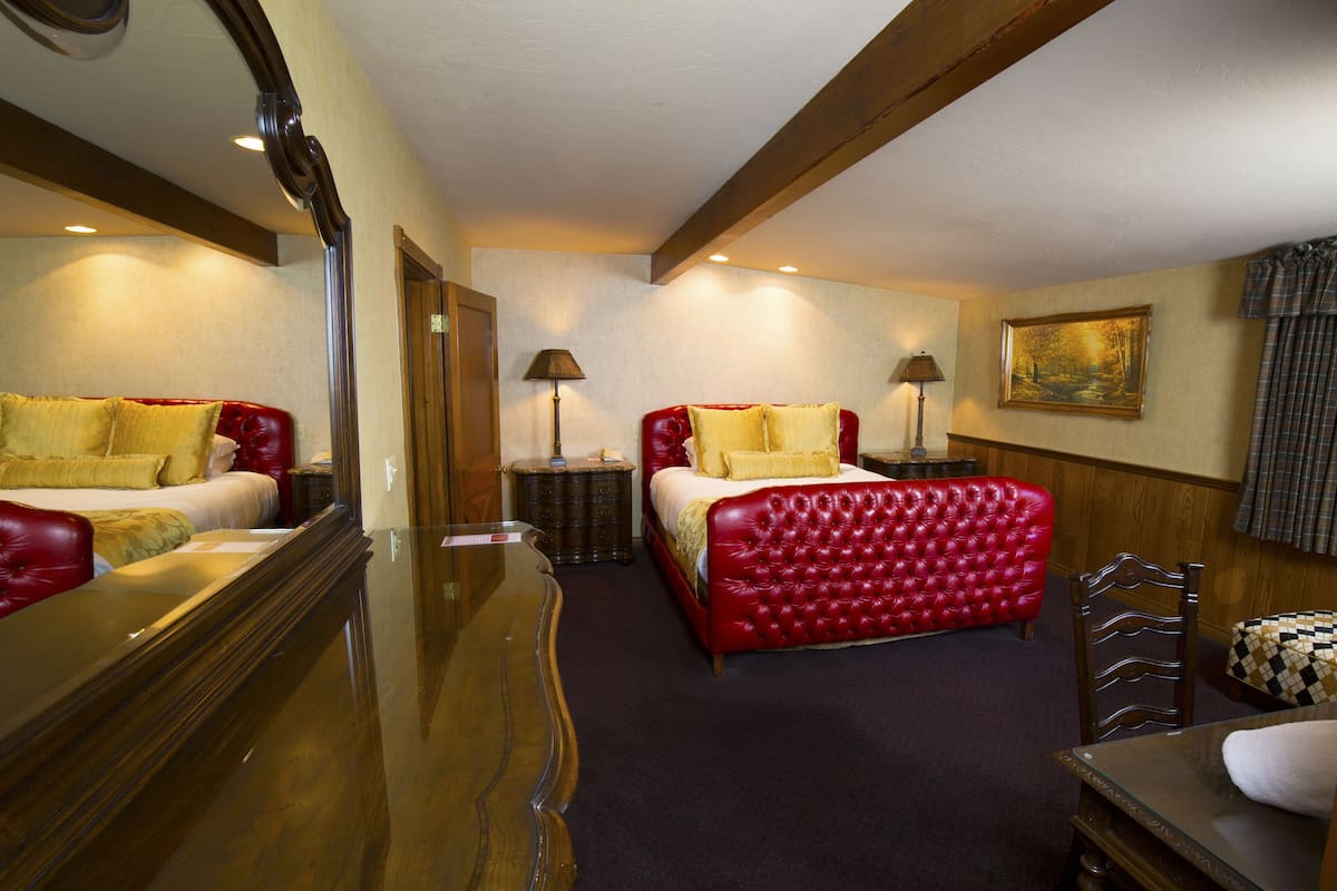 Ein Hotelzimmer mit zwei Betten, einem großen Spiegel, einer hölzernen Kommode und einem Bild an der Wand.