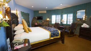 A bedroom with a large bed, a television, a desk, and a chair.