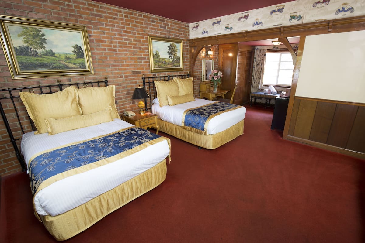Ein Zimmer mit zwei Betten, einer Ziegelwand und einem roten Teppich.