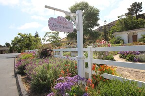 A sign for Madonna Inn Secret Garden, surrounded by a white fence and various colorful flowers.