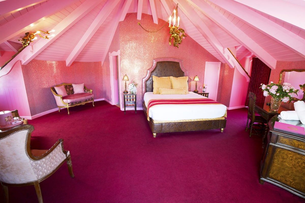 Ein Schlafzimmer mit einem großen Bett, einem Schminktisch mit Spiegel und einem Sessel.
