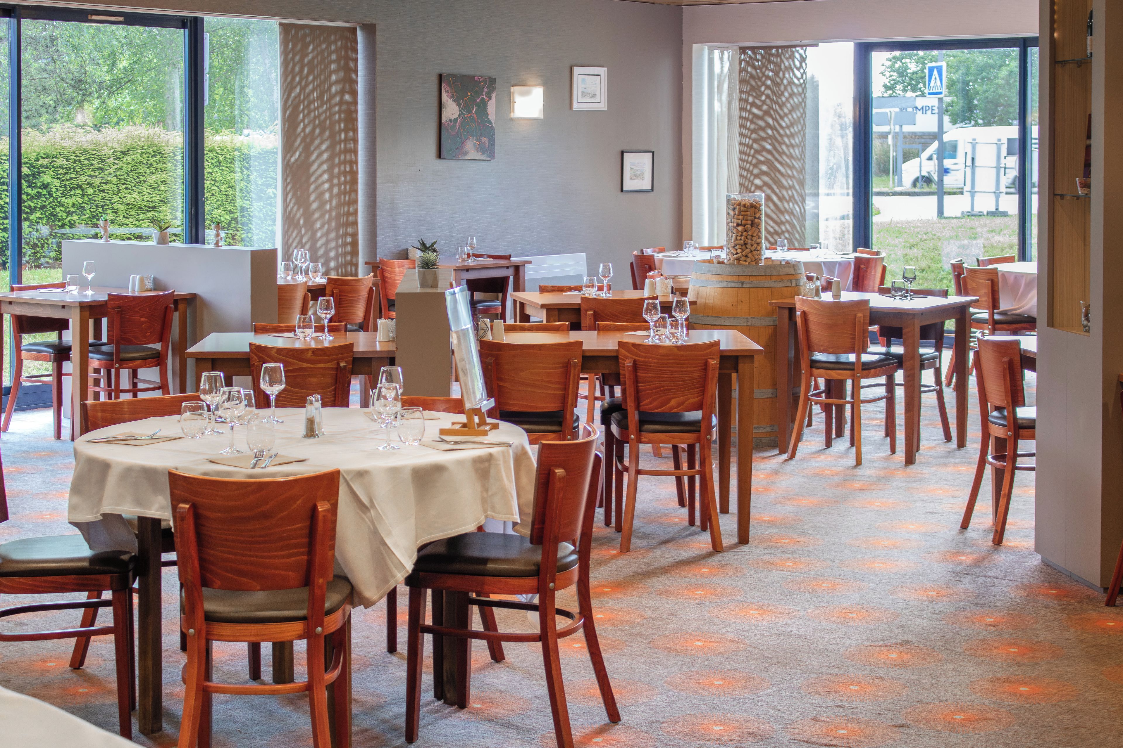 A restaurant with multiple tables and chairs, large windows, and a view of the outdoors.