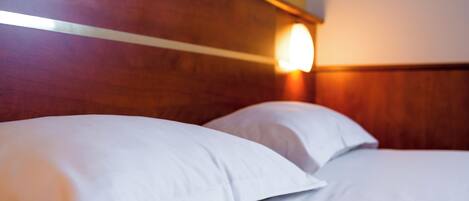A hotel room with a wooden headboard and a wall-mounted light fixture.