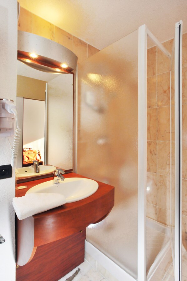 A bathroom with a wooden vanity, a sink, a mirror, and a glass shower enclosure. - Brit Hotel Rennes St Grégoire - Le Villeneuve (Saint-Gregoire)