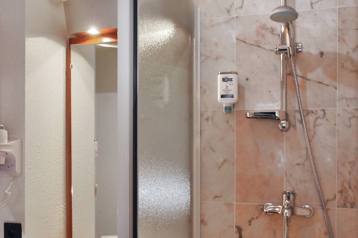 Une salle de bain avec une douche en marbre, un lavabo avec un miroir et une serviette posée sur le comptoir.