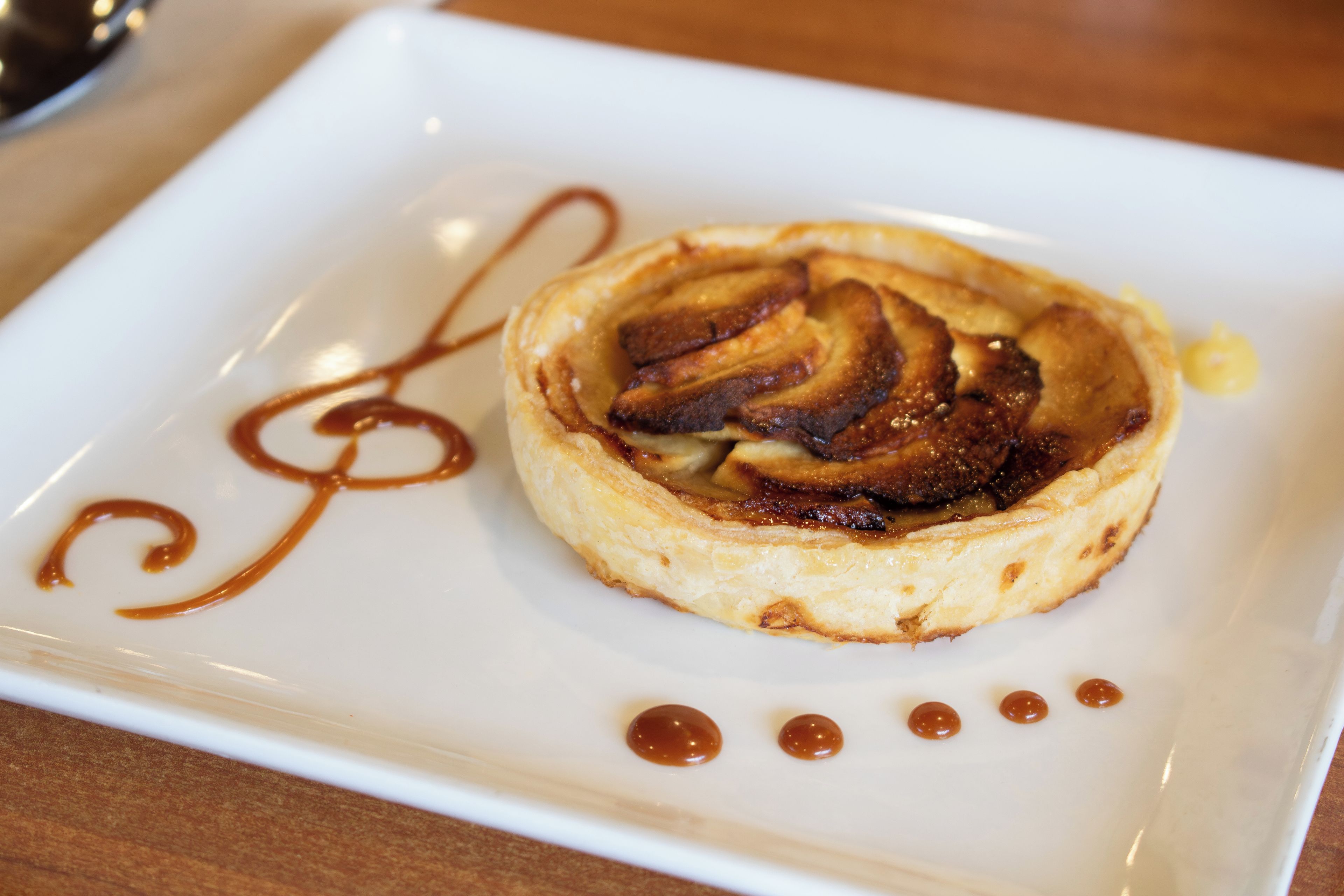 A dessert on a white plate with caramel drizzle and dots.