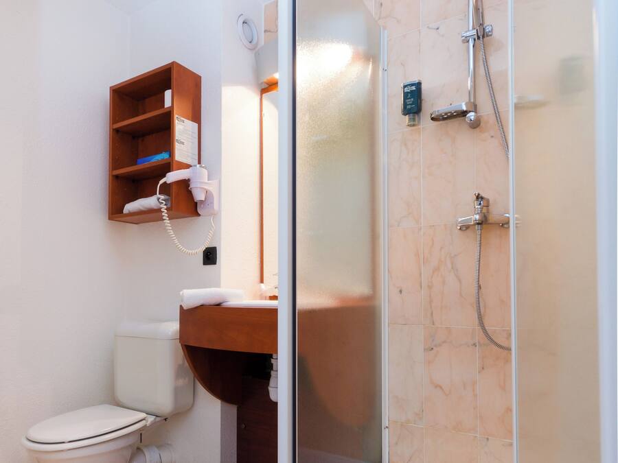 A bathroom with a toilet, a sink, a shower, and a glass-enclosed shower stall.