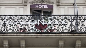 Fachada de un hotel con un balcón que presenta elaboradas barandillas de hierro forjado y un letrero que dice 'HOTEL'.