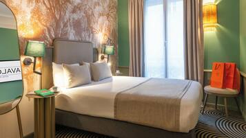 Habitación de hotel con una cama grande, dos mesitas de noche con lámparas, vista al exterior y un mural de un árbol en la pared.